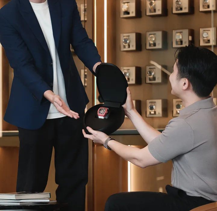 A seller handing over a watch to a Luxehouze specialist at the boutique